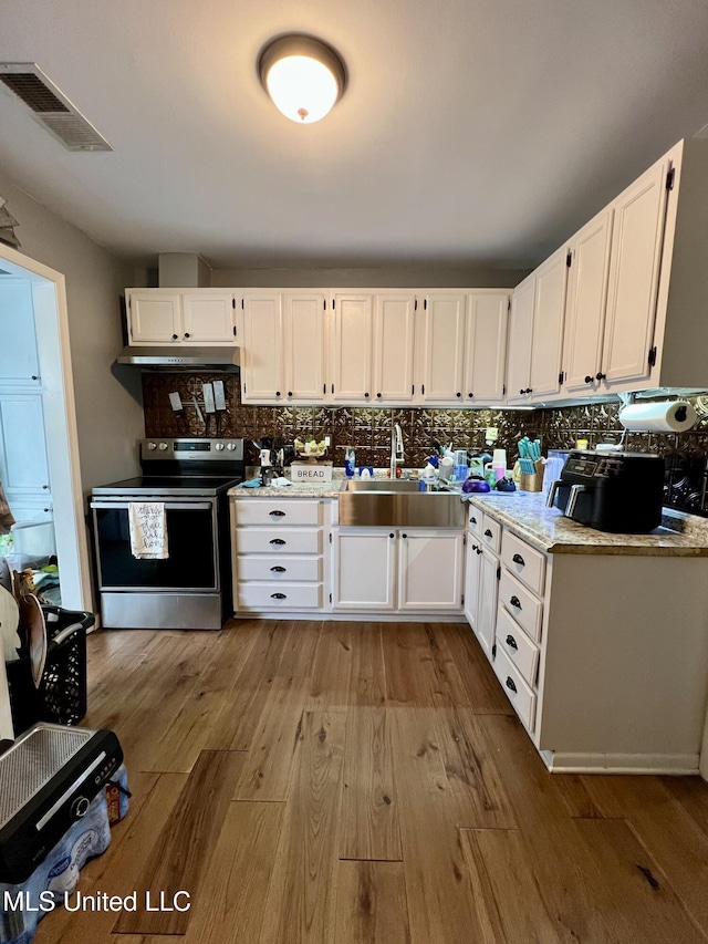 kitchen with light wood-style flooring, white cabinets, a sink, visible vents, and electric stove