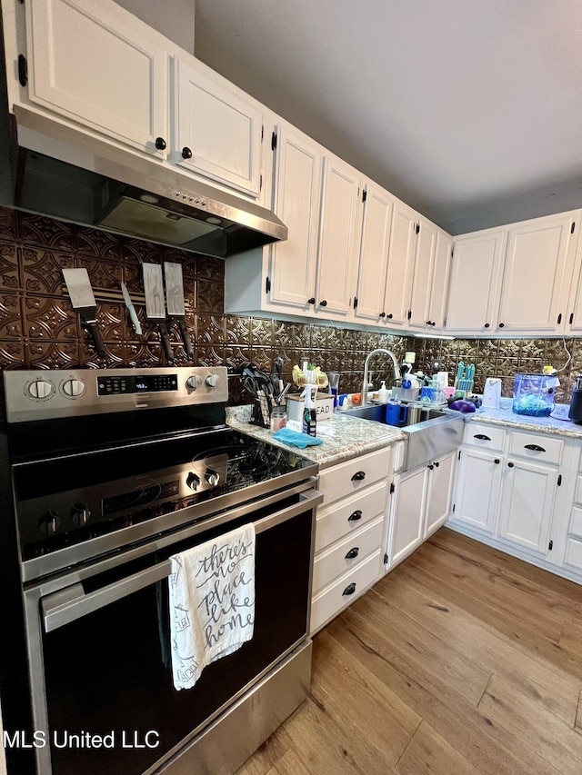 kitchen featuring light wood finished floors, white cabinets, under cabinet range hood, and stainless steel range with electric cooktop
