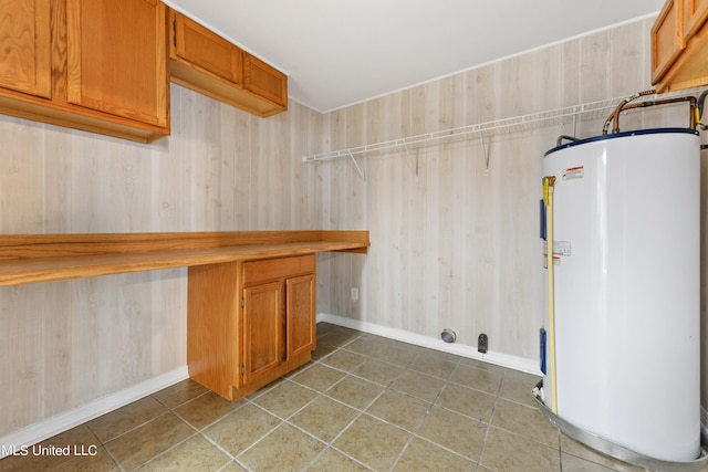 washroom with dark tile patterned flooring, wood walls, and water heater