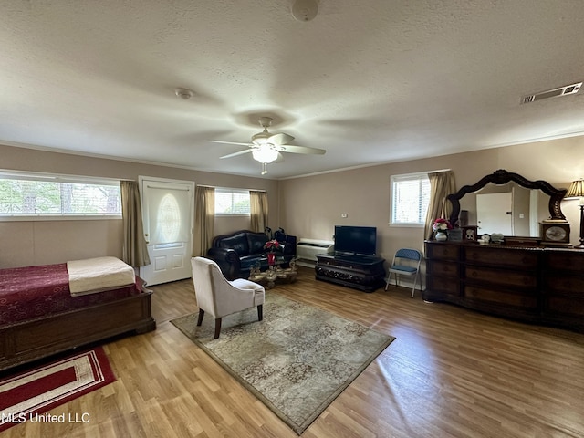 interior space featuring a textured ceiling, ceiling fan, light hardwood / wood-style flooring, and multiple windows