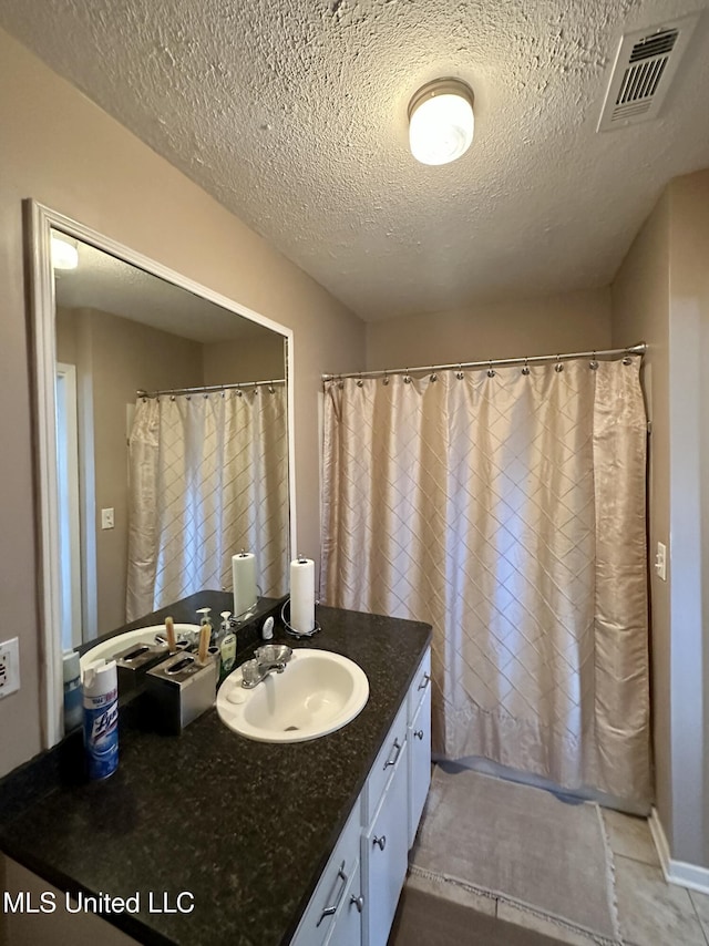 bathroom with curtained shower, vanity, and a textured ceiling