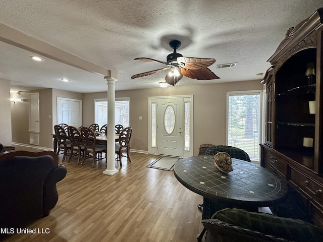 dining area with decorative columns, a textured ceiling, ceiling fan, and light hardwood / wood-style flooring