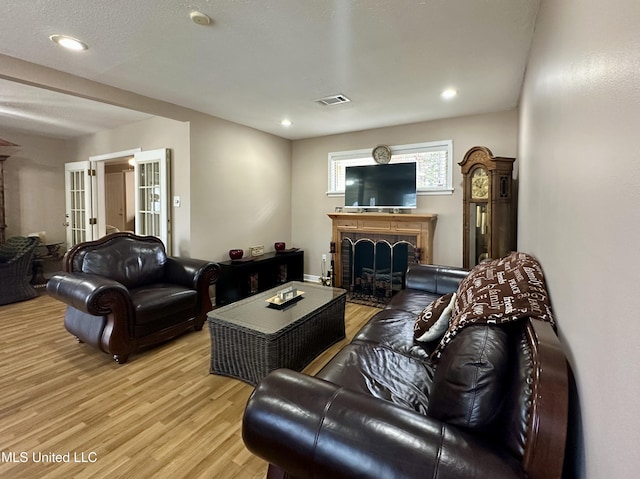 living room featuring french doors, a textured ceiling, and light wood-type flooring