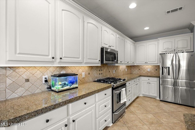 kitchen with visible vents, light tile patterned floors, decorative backsplash, appliances with stainless steel finishes, and white cabinetry