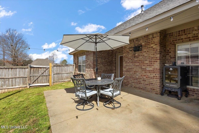 view of patio with a gate, outdoor dining space, and fence