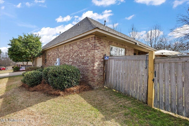 view of property exterior with a yard, brick siding, and fence