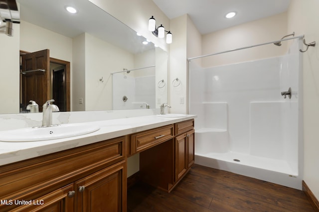 full bathroom with wood-type flooring, a shower, double vanity, and recessed lighting