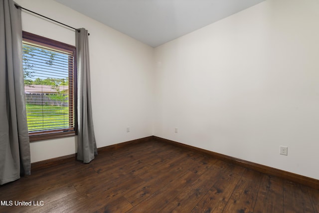 spare room featuring plenty of natural light, dark wood-style floors, and baseboards