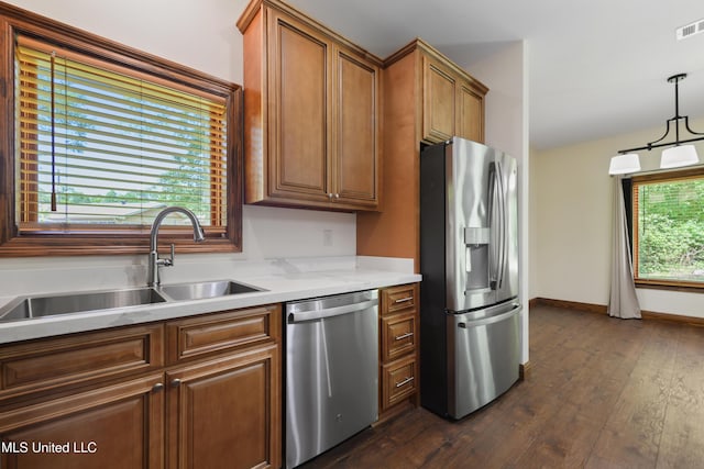 kitchen featuring appliances with stainless steel finishes, a sink, dark wood finished floors, and brown cabinetry