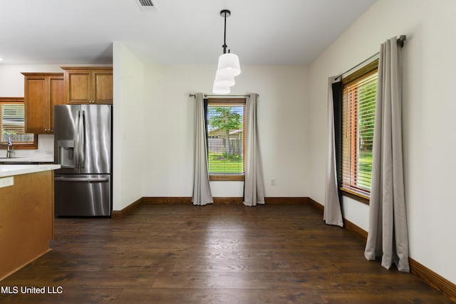 kitchen with stainless steel fridge, brown cabinets, dark wood finished floors, light countertops, and baseboards