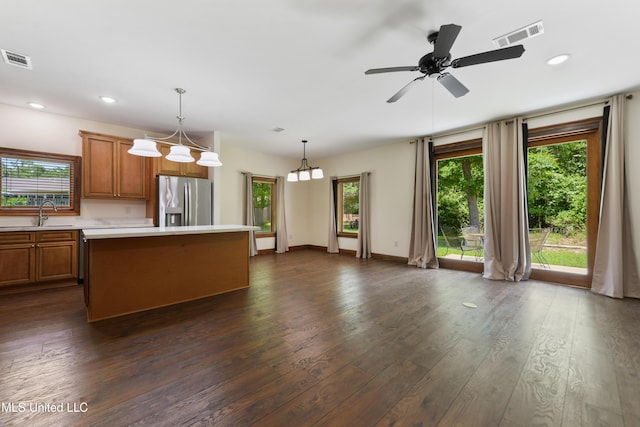 kitchen with stainless steel refrigerator with ice dispenser, light countertops, brown cabinetry, healthy amount of natural light, and recessed lighting