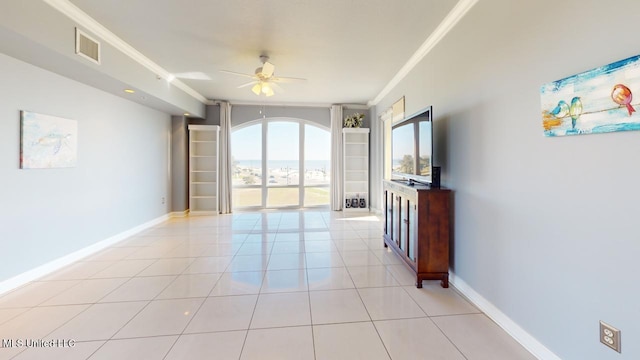 empty room with ceiling fan, crown molding, and light tile patterned flooring