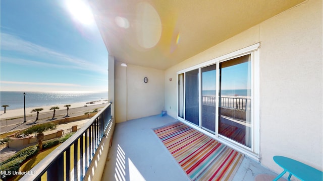 balcony featuring a beach view and a water view