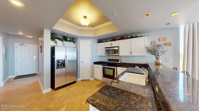 kitchen with appliances with stainless steel finishes, ornamental molding, a raised ceiling, sink, and white cabinets