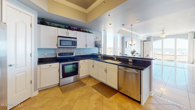 kitchen featuring sink, stainless steel appliances, light tile patterned floors, white cabinets, and ceiling fan with notable chandelier