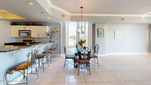 tiled dining area with ornamental molding and an inviting chandelier