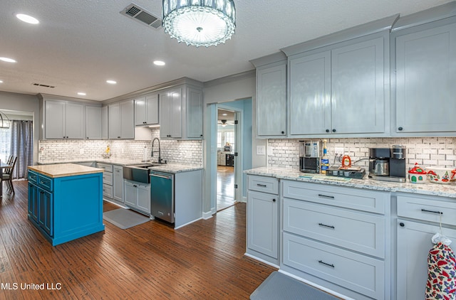 kitchen featuring visible vents, dark wood finished floors, a sink, stainless steel dishwasher, and a wealth of natural light