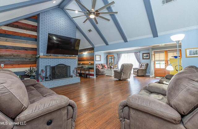 living area with beamed ceiling, wood-type flooring, a brick fireplace, and a ceiling fan