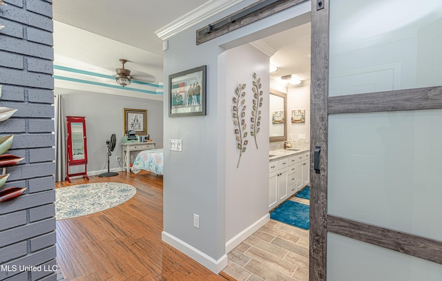 hallway featuring baseboards, light wood-style floors, and ornamental molding