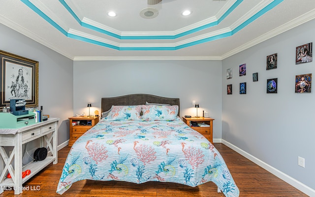 bedroom with baseboards, crown molding, a tray ceiling, and wood finished floors