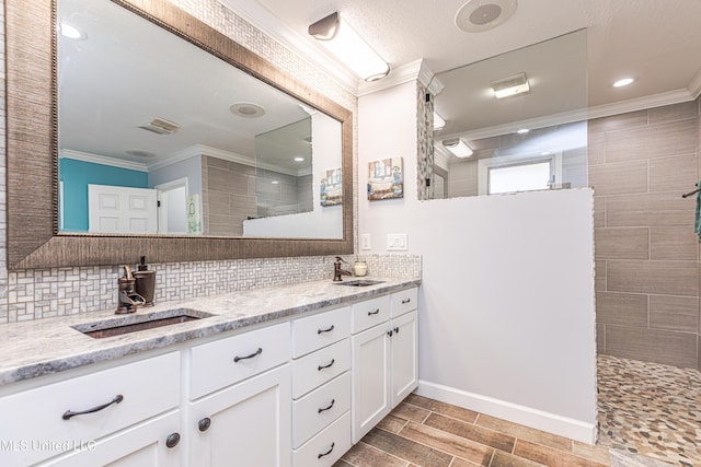 bathroom featuring decorative backsplash, crown molding, a walk in shower, and a sink