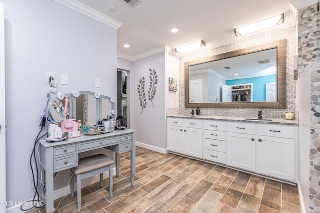 bathroom with wood finished floors, double vanity, a sink, crown molding, and tasteful backsplash