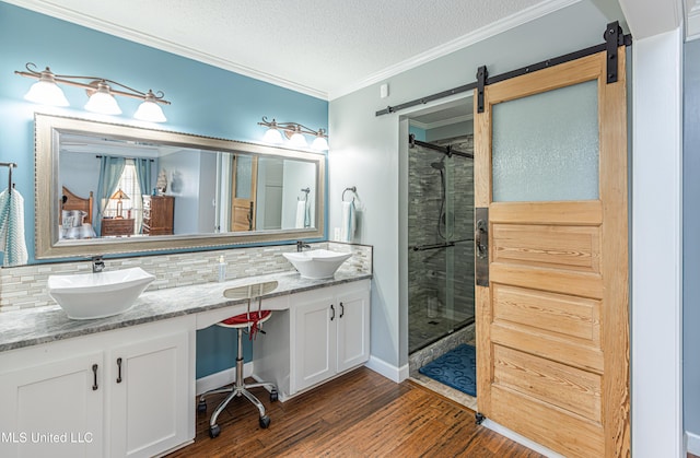 bathroom featuring backsplash, wood finished floors, crown molding, and a sink