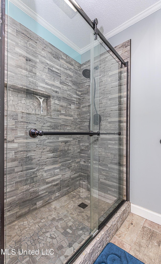 full bathroom with a textured ceiling, a stall shower, and crown molding