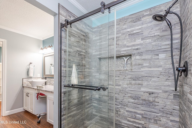 bathroom featuring a textured ceiling, wood finished floors, a shower stall, crown molding, and vanity