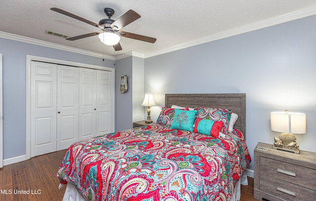 bedroom with wood finished floors, visible vents, a closet, a textured ceiling, and crown molding