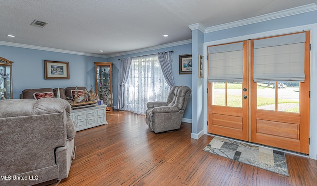 living room featuring visible vents, hardwood / wood-style floors, ornamental molding, and french doors