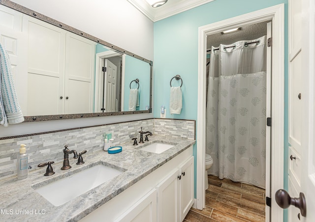 bathroom featuring a sink, decorative backsplash, toilet, and crown molding