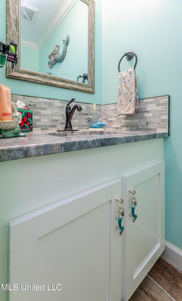 bathroom featuring vanity, wood finished floors, visible vents, and ornamental molding