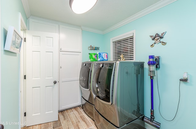 laundry area featuring washer and dryer, crown molding, cabinet space, and wood tiled floor