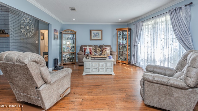 living room with visible vents, a textured ceiling, wood finished floors, recessed lighting, and crown molding