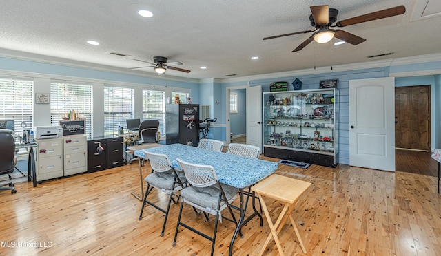 dining space with visible vents, light wood-type flooring, crown molding, and a ceiling fan