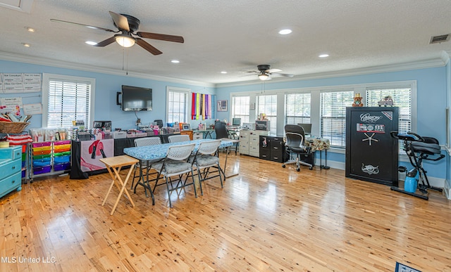 dining area with a healthy amount of sunlight, a ceiling fan, visible vents, ornamental molding, and wood-type flooring