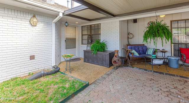 view of exterior entry with brick siding and a patio