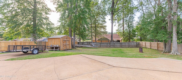 view of yard with a storage unit, an outbuilding, a fenced backyard, and a patio area