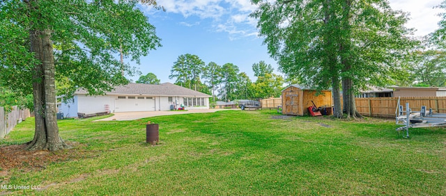 view of yard with an attached garage, a storage unit, a fenced backyard, and an outdoor structure