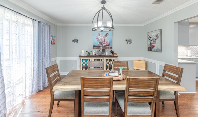 dining room featuring crown molding, light wood finished floors, and wainscoting