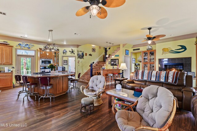 living room with ornamental molding, a fireplace, dark hardwood / wood-style floors, and ceiling fan