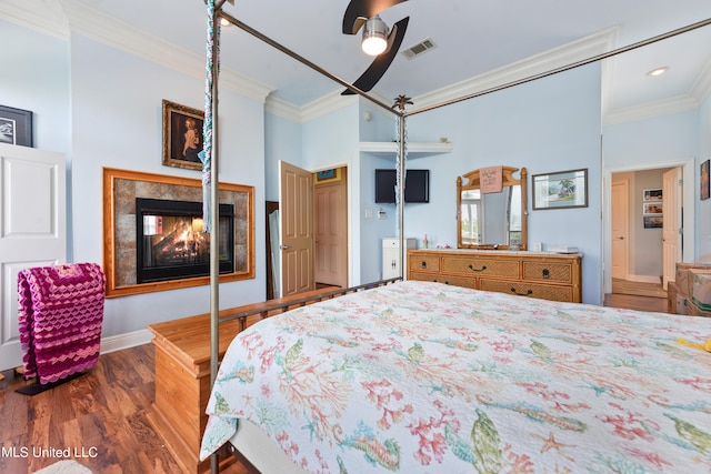 bedroom featuring dark hardwood / wood-style flooring, a multi sided fireplace, ornamental molding, and ceiling fan