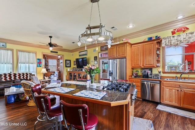 kitchen featuring a kitchen bar, dark wood-type flooring, sink, crown molding, and stainless steel appliances