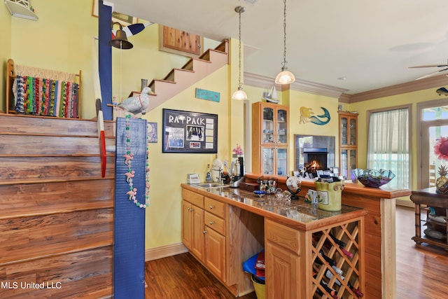 kitchen featuring pendant lighting, dark wood-type flooring, kitchen peninsula, and crown molding