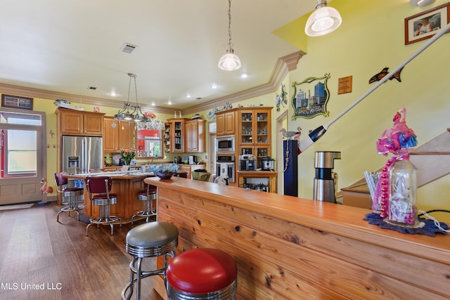 kitchen featuring a center island, a kitchen breakfast bar, stainless steel appliances, ornamental molding, and dark hardwood / wood-style floors