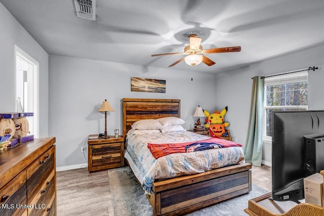 bedroom with light wood-style floors, visible vents, ceiling fan, and baseboards