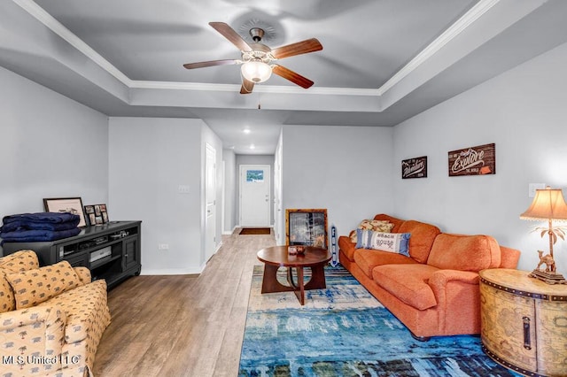 living room with crown molding, a tray ceiling, and wood finished floors