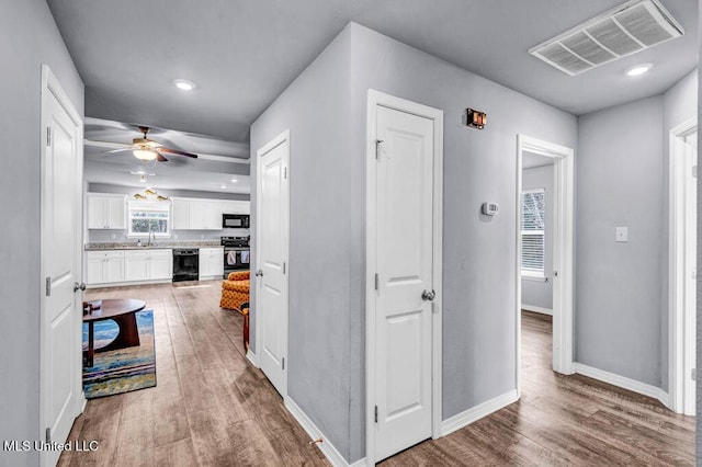 corridor featuring beverage cooler, baseboards, visible vents, wood finished floors, and a sink