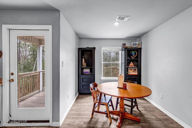 dining space with wood finished floors, visible vents, and baseboards